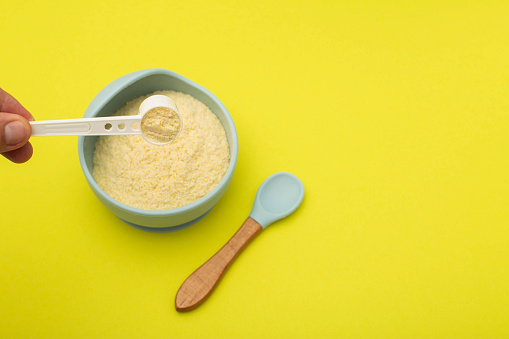 cooking wheat dairy-free porridge in a plate on a yellow background. The concept of proper and healthy nutrition for children.