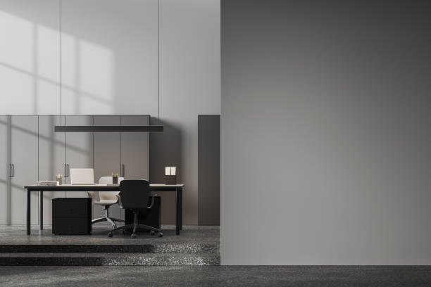 istock Grey office interior with work table and laptop computer, shelf and mock up wall 1864543320