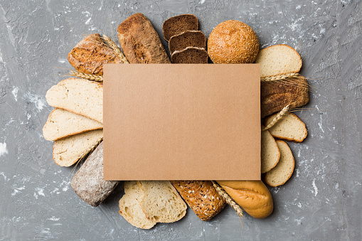 Minimalist paper blank mockup on background of Types of homemade bread. Different kinds of fresh bread as background, top view with space for your text or design.