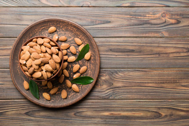 istock Fresh healthy Almond in bowl on colored table background. Top view 1864549714