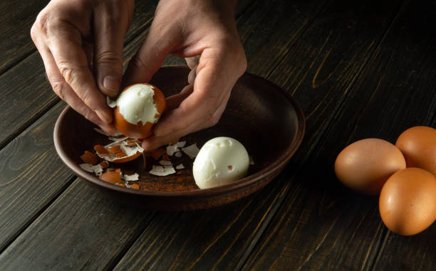 istock Cooking a delicious lunch with boiled eggs on the kitchen table. Shelling an egg with the hands of a cook. Advertising space. 1864552453