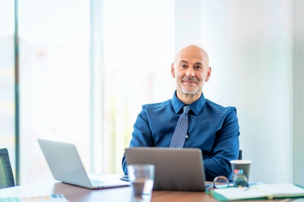 istock Mid aged businessman sitting in a modern office and using laptops for work 1864557225