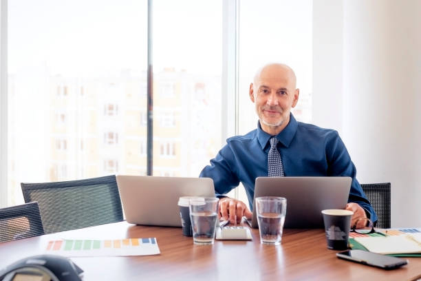 istock Mid aged businessman sitting in a modern office and using laptops for work 1864557227