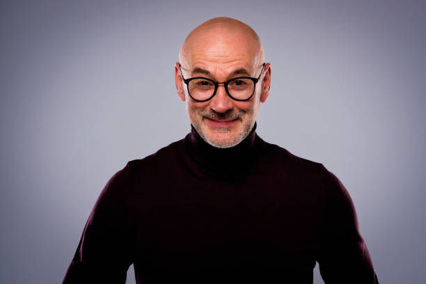 istock Bald mid aged man wearing turtleneck sweater and standing against isolated grey background 1864563541