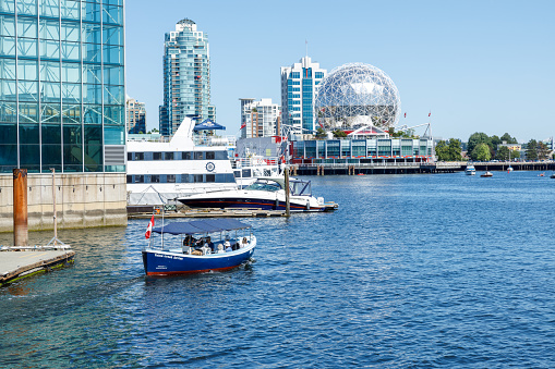 Vancouver, Canada - July 1,2023: View of False Creek Ferries boat full of passengers on a sunny day with zscience World in the Background