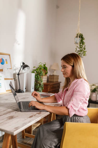 istock Woman sitting at home office desk, using laptop 1864571454