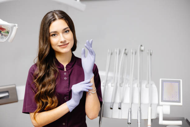 caucasian female dentist putting on blue sterilized surgical gloves in the medical clinic. - scrub brush fotos fotografías e imágenes de stock