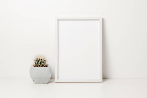 istock Photo frame mockup with cactus in pot on white wooden table 1864573078