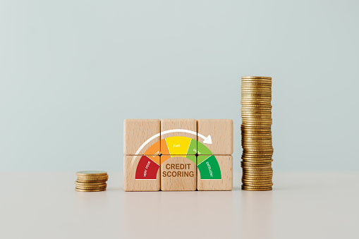 CREDIT SCORING text with indicator gauge meter on wooden cube block with stack of coin
