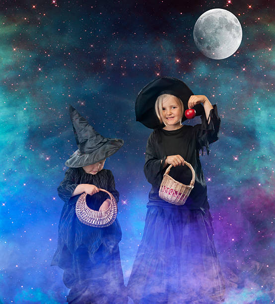 istock two little halloween witches on a space with moon background 186459103