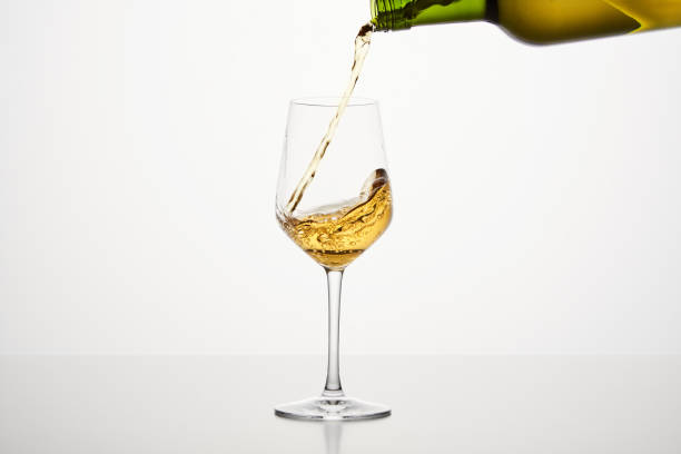 istock White wine pouring from green bottle, close up shot on white isolated background. 1864602966