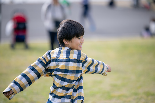 Little boy running on grass field in public park