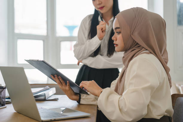 istock Two multi ethnic female office workers discussing financial market data and comparisons in the office. 1864616672