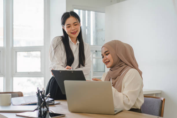 istock Two multi ethnic female office workers discussing financial market data and comparisons in the office. 1864616673