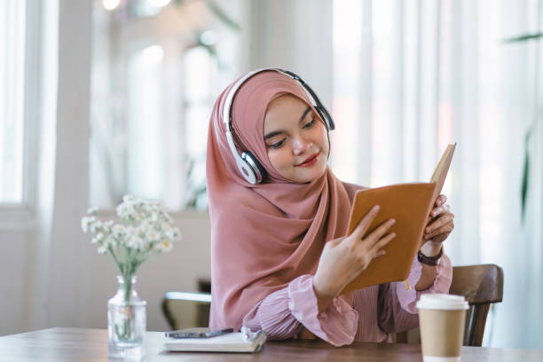 istock An Asian Muslim university student relaxes while reading a book at home. 1864617765