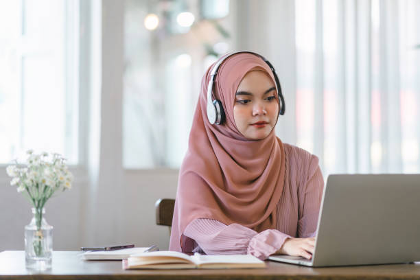 istock Asian Muslim university student studying remotely, using laptop and listening to online lecture. 1864617771