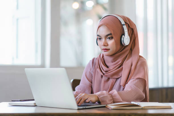 istock Asian Muslim university student studying remotely, using laptop and listening to online lecture. 1864618056