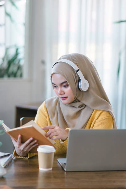 istock An Asian Muslim university student relaxes while reading a book at home. 1864618310