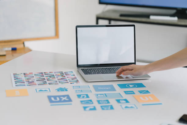 istock Creative UX UI designer working on screens for mobile responsive website development, focusing on UI UX. Developing wireframe sketch layout designs on a smartphone screen. 1864623661