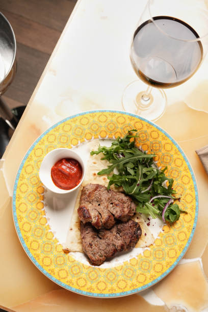 istock Grilled ribeye beef steak with red wine, herbs and spices on stone table 1864651992