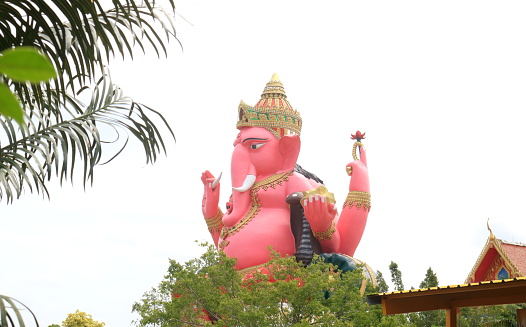 Pink Ganesha concrete statue sitting posture and sky background, beside view.