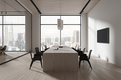 Cozy glass meeting interior with seats and negotiation table, laptop and tv display on wall. Business conference room with panoramic window on Kuala Lumpur skyscrapers. 3D rendering