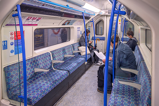 London Subway, London, England - November 12th 2023:  Three people sitting in a almost empty car in the London Subway