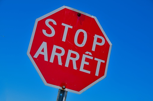 French and English Stop Sign on a Blue Sky background