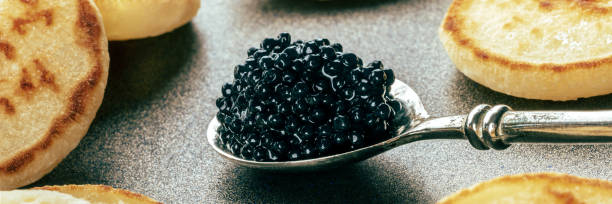 istock Silver spoon with caviar closeup with blinis panorama, an elegant appetizer 1864683713