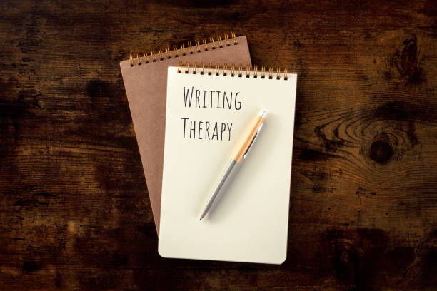 istock Writing Therapy. Notebook with a pen, overhead flat lay shot on a wooden desk 1864685447