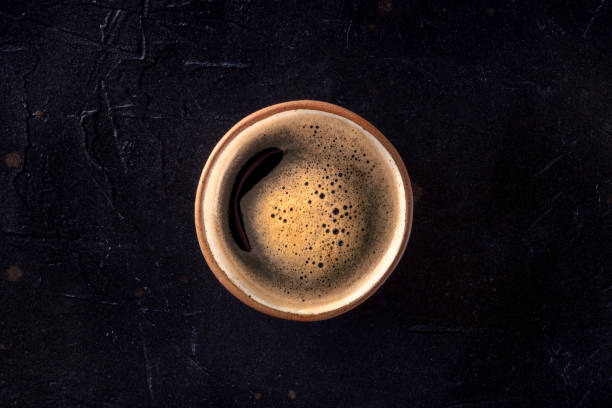 A cup of black coffee with froth, overhead flat lay shot A cup of black coffee with froth, overhead flat lay shot on a dark background black coffee from above stock pictures, royalty-free photos & images