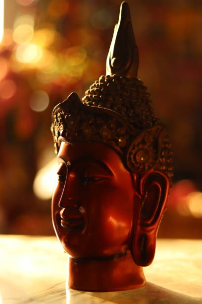 istock A Red and brown colored Buddha Statue or figurine in golden hour sunlight with selective focus, Diagonal side shot 1864691552