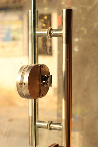 A Closeup shot a Big silver or steel door handle and lock of glass toughened door with selectively focus, side shot