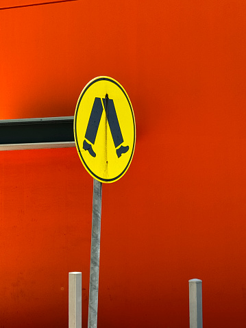 Pedestrian sign in front of red wall