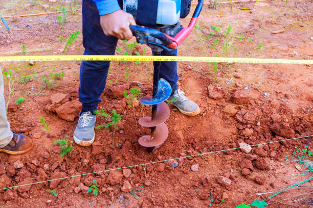 istock In order to install fence posts, worker digs ground with a gasoline drilling machine 1864782247
