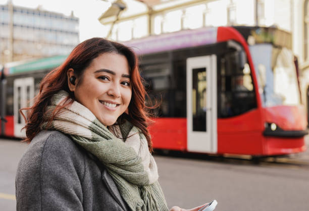 istock Happy young asian woman smiling on camera while using mobile phone during winter time in the city with tram in the background - Travel concept 1864796685