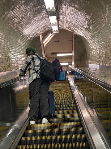 New York, NY USA -December 18, 2023: New York City,  Person with Luggage on Subway Escalator And Tunnel