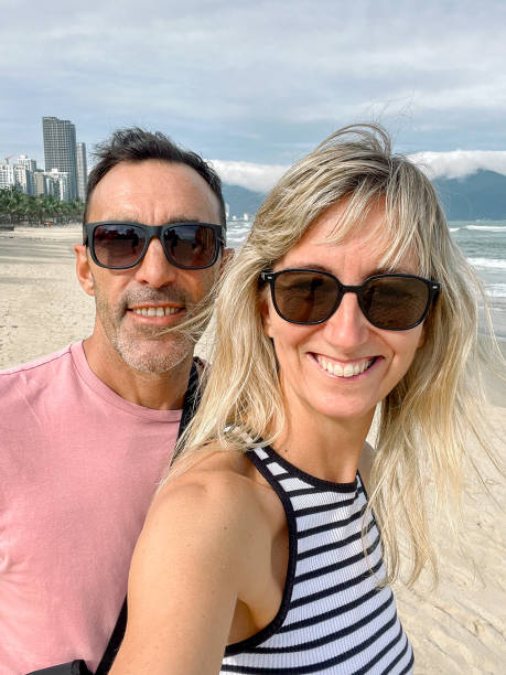 istock Man and young woman taking a selfie on the beach 1864809045