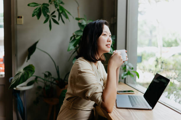 istock Asian woman enjoying coffee while working in cafe 1864822402