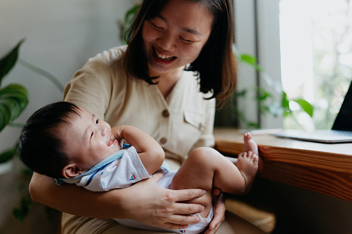 An Asian Chinese woman embracing her baby boy and having fun