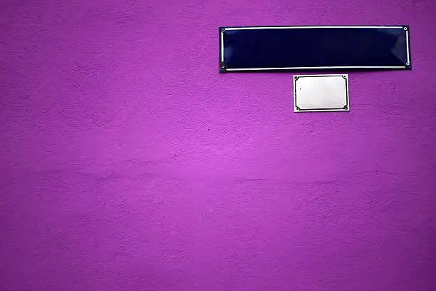 Color shot of an empty blue street sign on a magenta wall