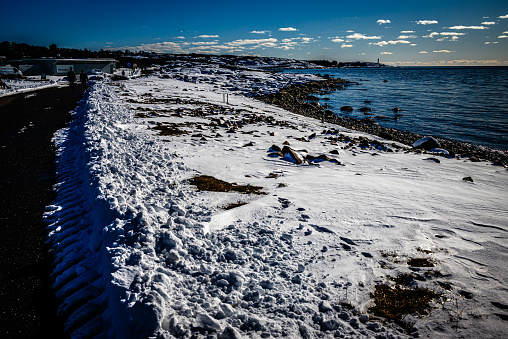 Coastline covered with ice and snow with unknown walking people