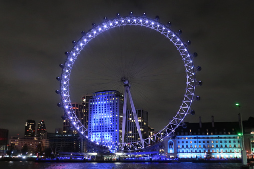 London, United Kingdom, 17 December 2023. Millenium wheel and River Thames Southbank illuminated with lilac purple light. Outdoor on a winter night