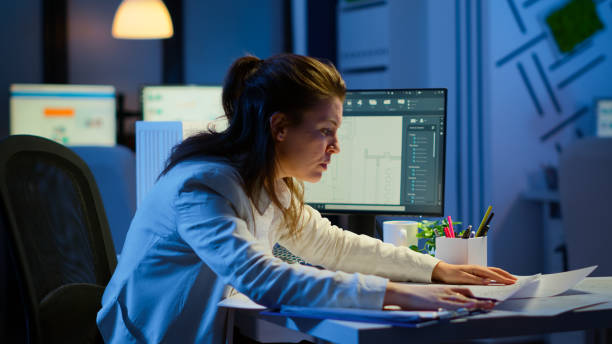 istock Focused woman architect checking and matching blueprints overtime 1864859177