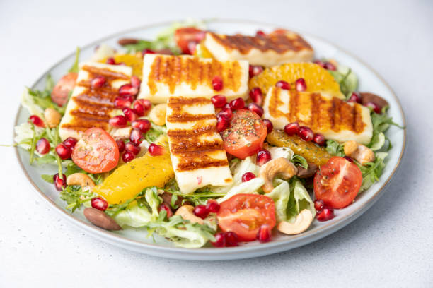 Warm salad with grilled halloumi cheese, nuts (cashews and almonds), cherry tomatoes, pomegranate, orange and arugula. Traditional Oriental Cheese