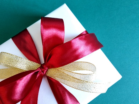 Gift ribbon and bow in white satin laid on badly torn red textured craft paper.  Alternative version shown below: