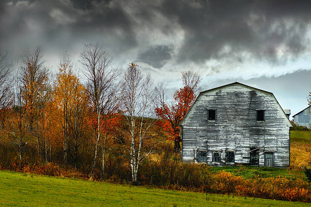 A rustic red barn with weathered wooden walls and a rusty corrugated metal roof, located near the scenic city of Bodoe in Nordland, north of the Polar Circle, Norway. Captures rural charm.