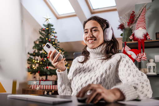 Portrait of a cheerful woman using a computer, mobile phone and headphones - Wireless technology concept