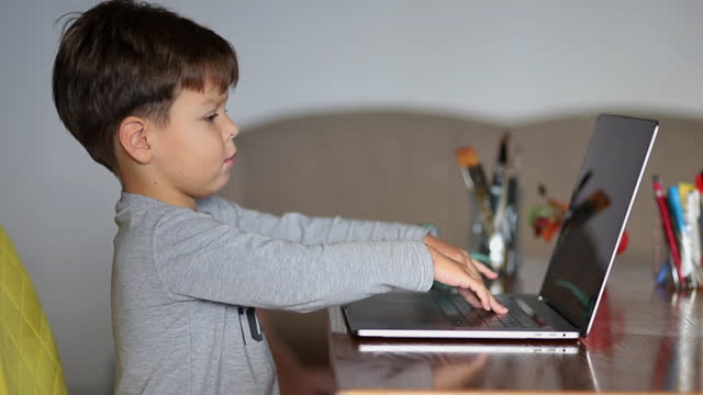 A boy imitates working on a laptop. Home space. Adult imitation concept.