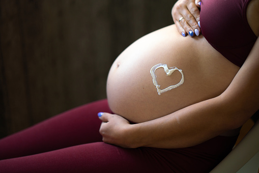 Close-up of a belly of unrecognizable pregnant woman with heart symbol